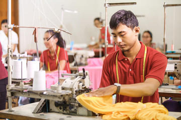man sewing on a sewing machine at a clothing factory
