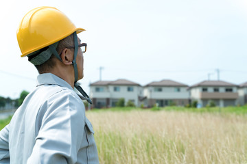 住宅街と更地を見つめる不動産デベロッパー