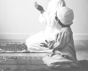 Muslim boy learning how to make Dua to Allah - obrazy, fototapety, plakaty
