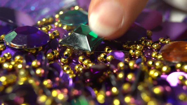 Extreme closeup of glue oozing onto purple costume and a finger pressing and holding a rhinestone into place.