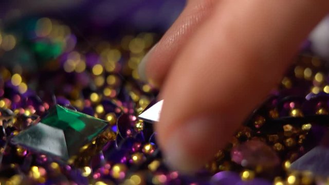 Extreme closeup of glue oozing onto purple costume and a finger pressing and holding a rhinestone into place.
