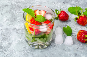 Cold summer drink with strawberries, lemon and mint