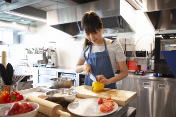 調理場で野菜を切り料理の下ごしらえをする女性