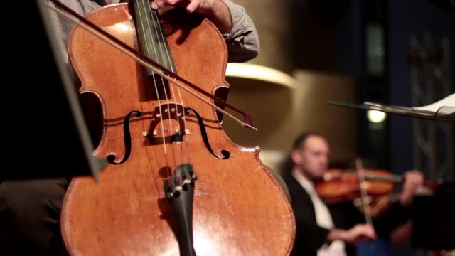 Symphony orchestra on stage, conductor, violins, cello and flute performing.