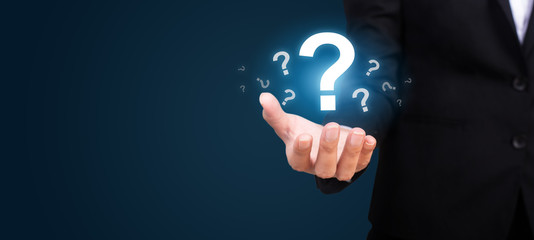 businesswoman on blurred background holding hand question marks