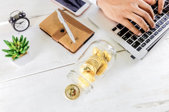 Bitcoin coin golden coin in the glass jar on wooden table ,Man using tablet for trading cryptocurrency or bitcion.Set of cryptocurrencies with a golden bitcoin