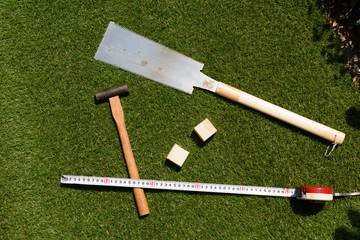 tools(hammer, wood, handsaw, measure) on turf