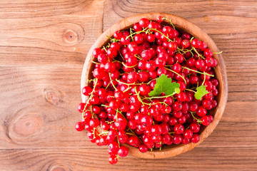 Fresh red currant in a wooden plate on a table. Top view