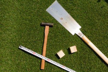 tools(hammer, wood, handsaw, measure) on turf