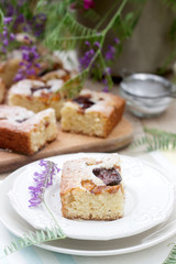 Pieces of fruit pie with pieces of plums and peach and a bouquet of flowers on a wooden table. Rustic style.