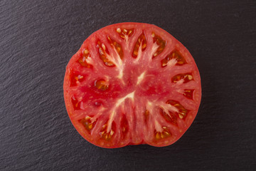 Red tomato slice in black background, top view, closeup, macro