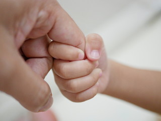 Little baby hand holding father's finger representing father-and-child love, intimacy, and assistance