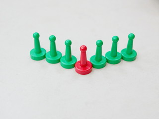 Green tokens in a row with the only one red token representing being different and unigue among many others