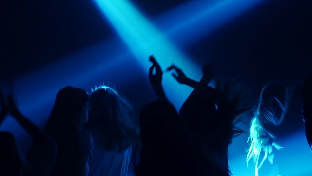 Teens on the dancefloor in color music on concert . Silhouette. Slow motion