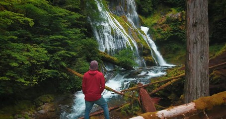 Aerial over hiker at forest waterfall in oregon