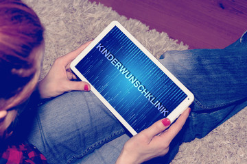 Eine Frau sucht an einem Tablet PC nach einer Kinderwunschklinik