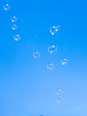 Soap bubbles in flight against the blue sky