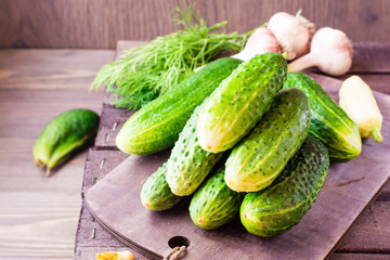 A bunch of fresh cucumbers, dill and garlic on a wooden table. Rustic style