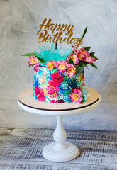 Tropical birthday cake on a cakestand with a topper