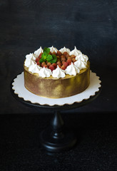 gilded chocolate cake with merengues, raspberries and mint leaves