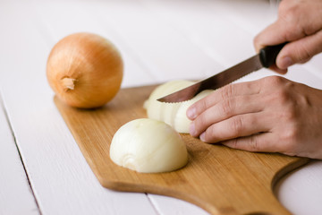 Women's hands cut onions