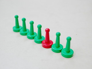 Green tokens in a row with the only one red token representing being different and unigue among many others