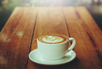 Cup of latte art coffee on wooden floor. vintage color tone.