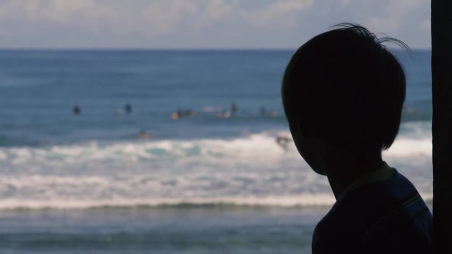 180p Slow motion shot of Silhouette of boy watching surfer riding waves