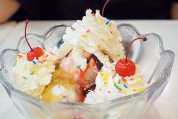 ice cream in glass bowl with whipped cream and red cherry on top