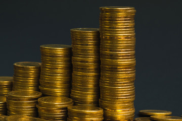 Savings, increasing columns of coins, piles of coins arranged as a graph in dark room, business banking concept.