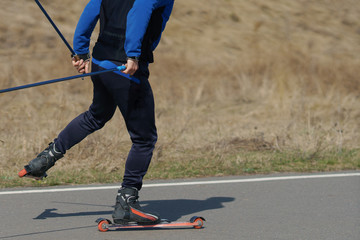 Fototapeta na wymiar man on summer skis is riding on an asphalt road