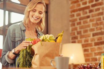 Being glad. Amazing female person keeping smile on her face and bowing head while bringing fresh...