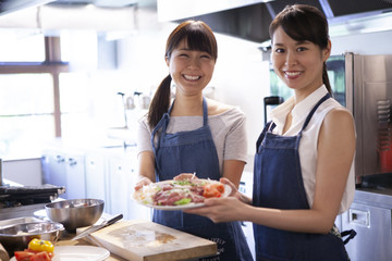 完成した料理を持ち微笑む二人の女性のポートレート