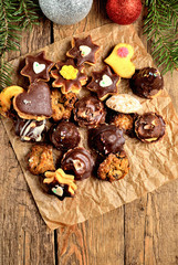 View from above of christmas sweets with different types of candy on baking paper and Christmas decorations in background vertical photo