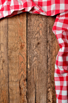 Red checkered tablecloth top and right frame on vintage wooden table background - view from above - vertical photo
