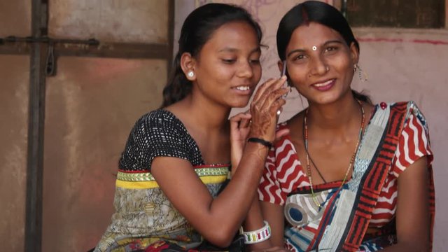 Tilt up to happy friends at home with a smart phone mobile talking looking at camera they share happy news laugh smile joy happiness fun togetherness bonding sharing caring ethic wear traditional