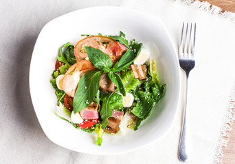 Salad with grilled tuna, quail eggs and fresh vegetables in white plate
