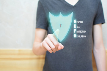 Man hand pressing locked shield button with keyhole on virtual touchscreen interface with copy space on wall. GDPR general data protection regulation concept.