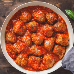 Meatballs with tomato sauce in a white iron pan over white background. Modern style. Top view.