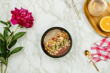 Flatlay of healthy breakfast: vegan smoothie bowl with chia pudding topped with granola, kiwi, pine...
