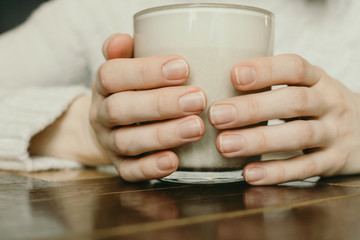 Fototapeta na wymiar Closeup of woman's hands holding cup with warm beverage, selective focus