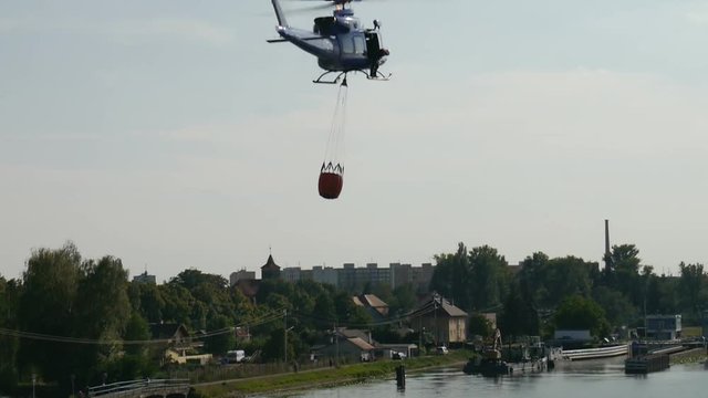 The fire brigade rescue helicopter flying in to fill up with water from a river.