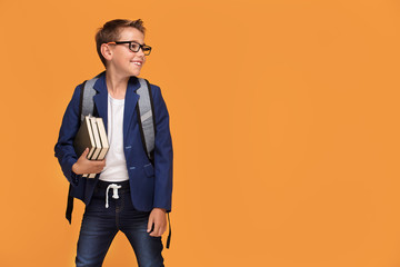 Little school boy with backpack and books.