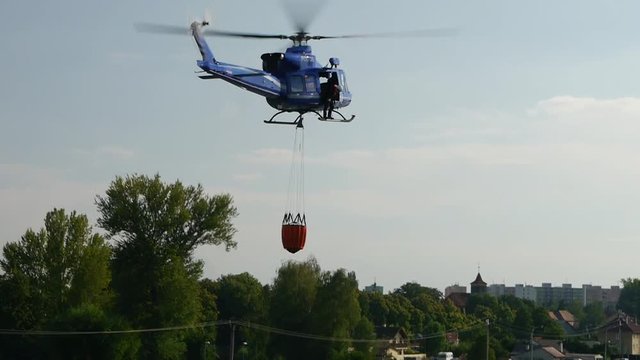 The helicopter collects water in the river to extinguish a fire.