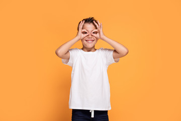 Fototapeta na wymiar Young emotional little boy on orange studio background.