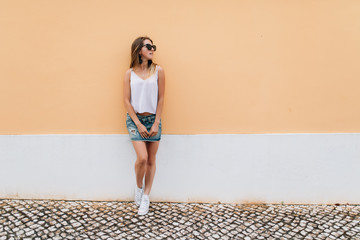 Happy pretty woman in the city. Beautiful young girl posing against orange wall