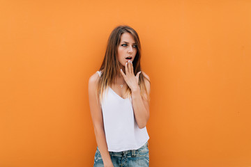 Surprised happy beautiful woman looking sideways in excitement, isolated on orange background