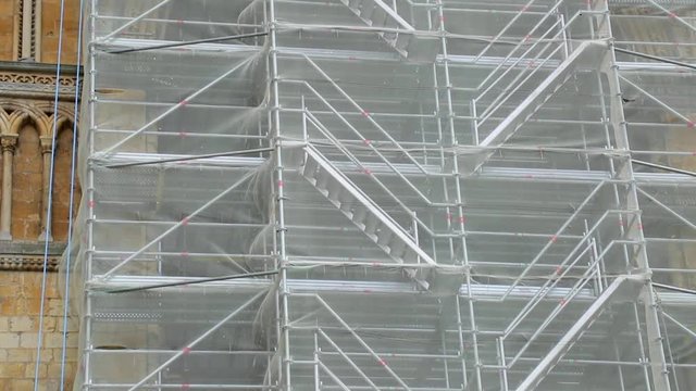 The netting of scaffolding on a cathedral blowing in the wind in slow motion.