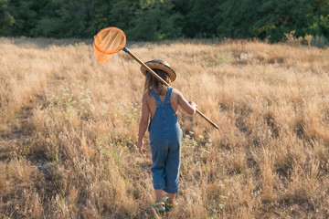 Child with a insect net catches butterfly