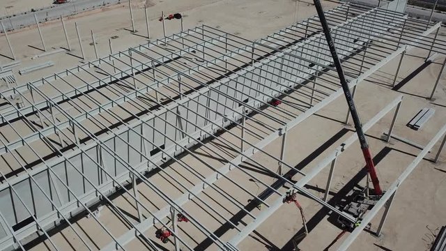a&eacute;reo , volando sobre las columnas de un tejado de una nave industrial en construcci&oacute;n, gr&uacute;a y operarios trabajando